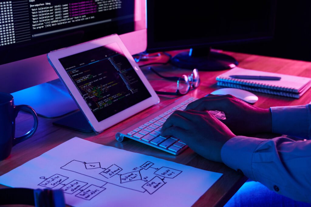 A man writing on a laptop in a purple theme with codes on the laptop