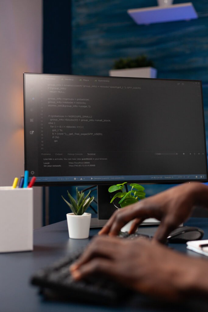 Hands writing on a keyboard with coding on the computer's screen