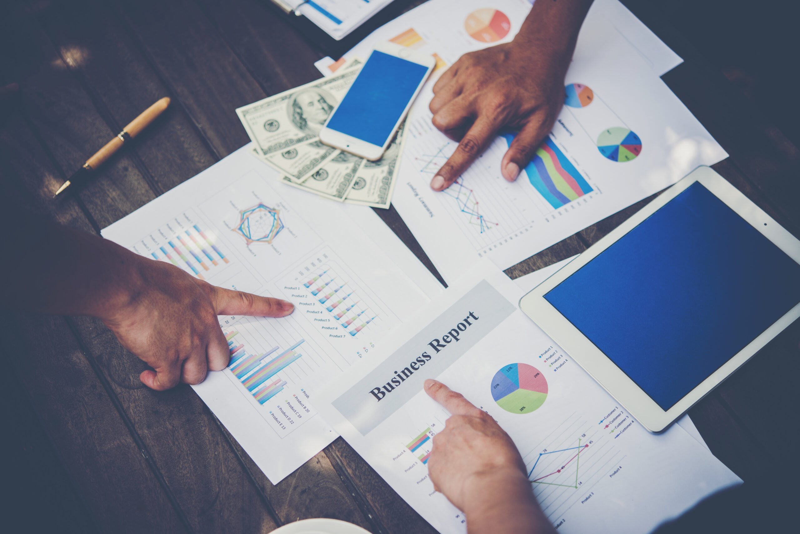 Employees discussing data in a meeting with their hands pointing to paper