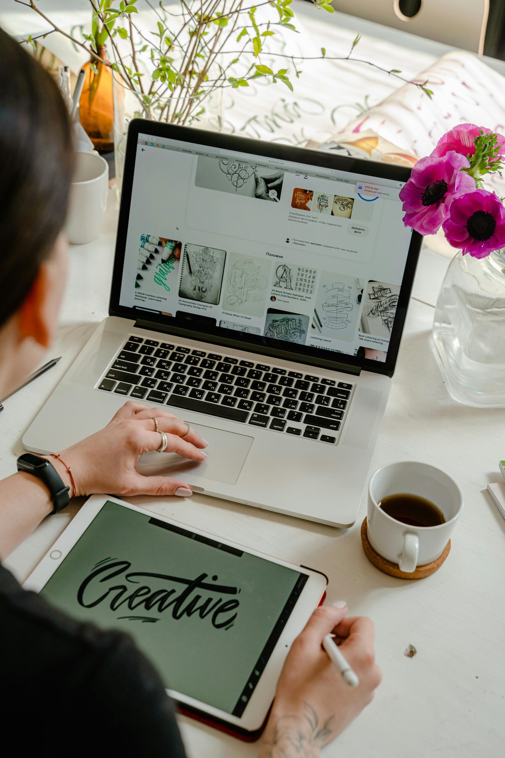 A woman sitting on her laptop and the iPad in front of the laptop has the word creative