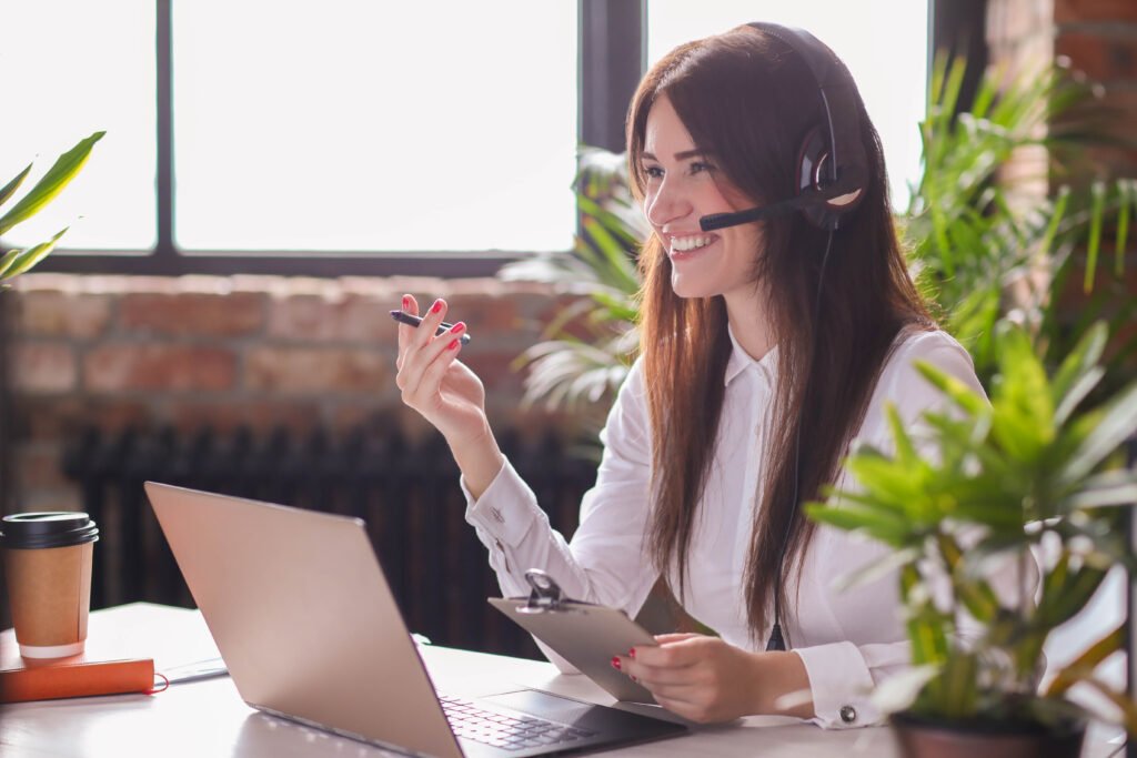 A woman wearing here headset and smiling while calling a customer