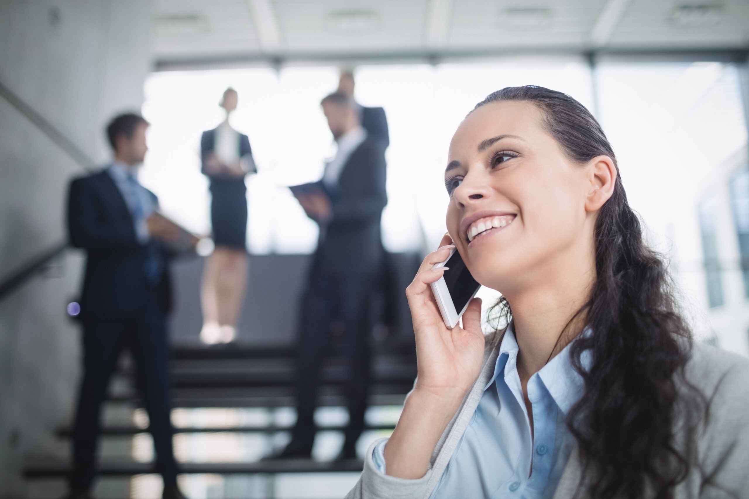 Business woman calling on her mobile [hone and business men in the background