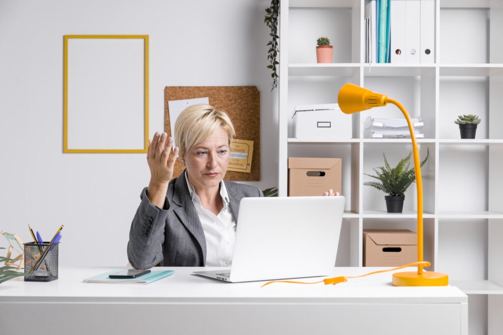 A professional woman setting on her desk and calling a client on her laptop