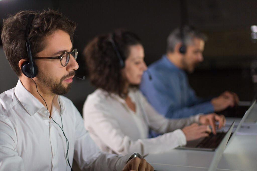 Employee wearing his headset on a call with client and two other employees in the background