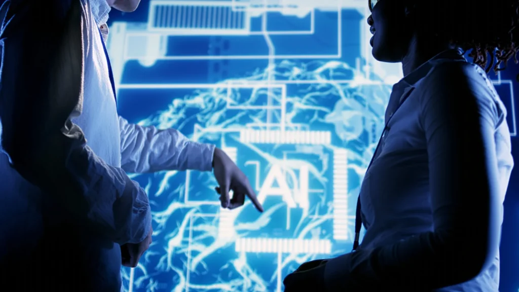 Two AI experts engage in a discussion in front of a vibrant electric blue hologram, showcasing a digital brain with the word 'AI' prominently displayed within it. The scene captures the essence of cutting-edge technology and innovation in artificial intelligence.