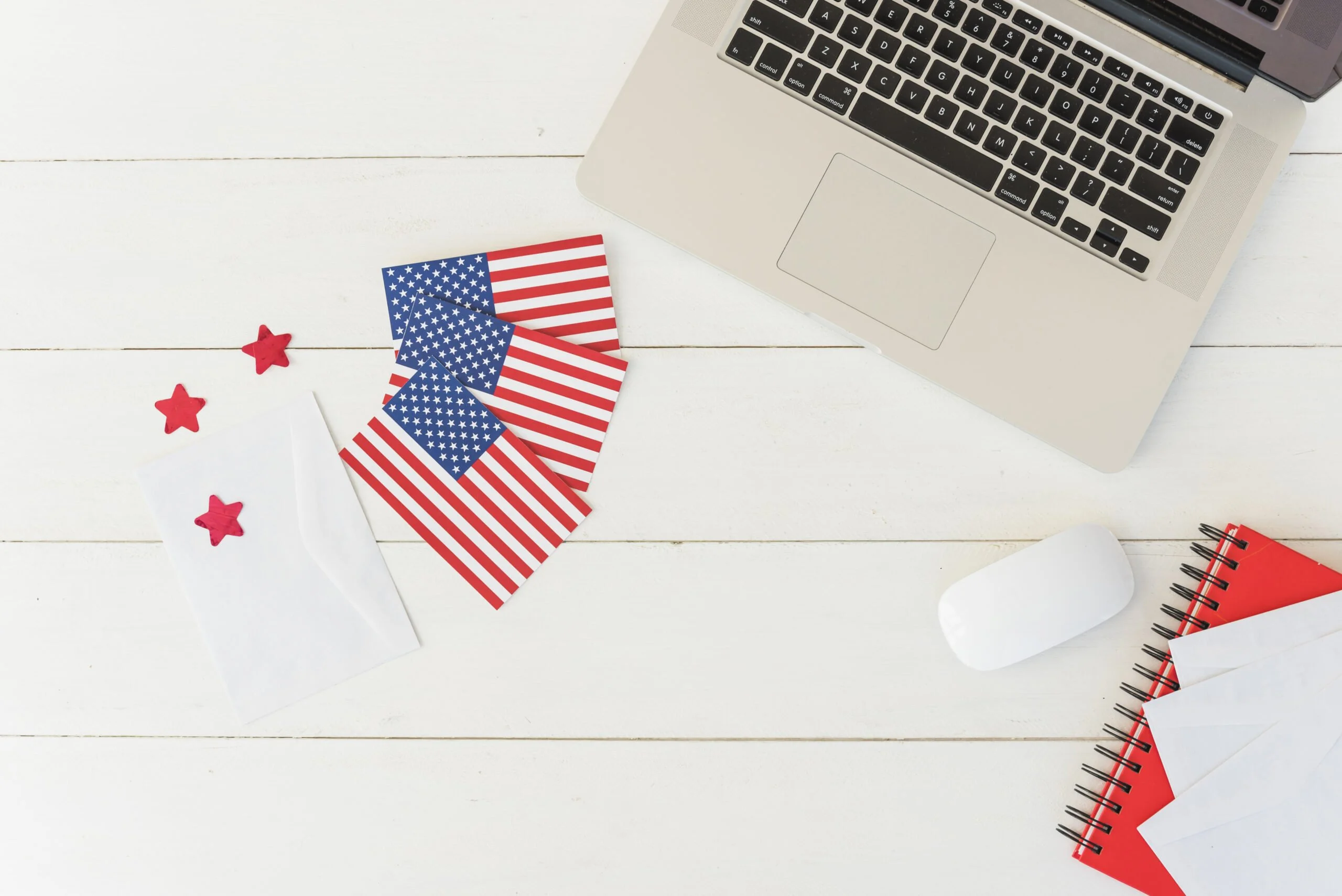 A laptop on a white table with American flag and a notebook beside it