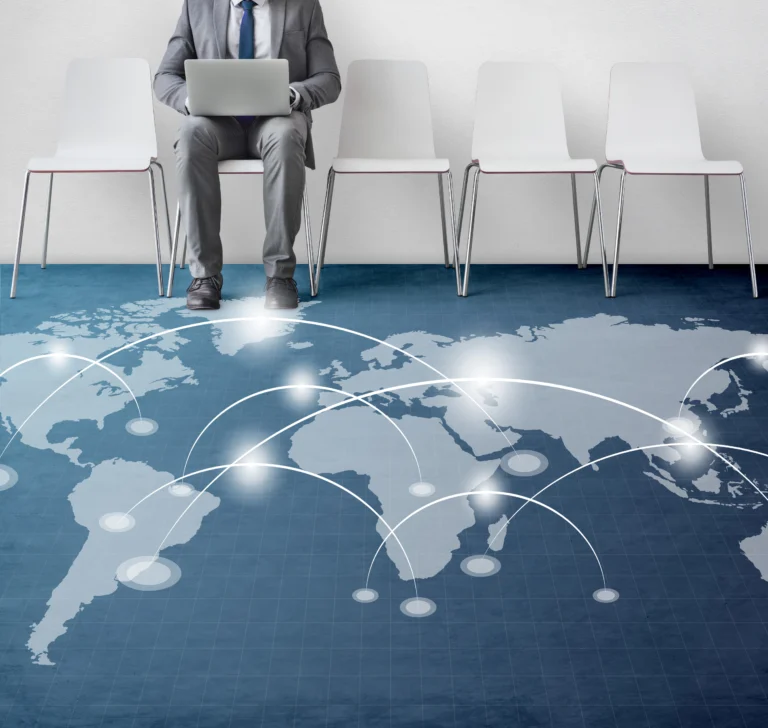 A man sitting on a chair, with a world map printed on the floor beneath him, illustrating global networking and connections between countries.