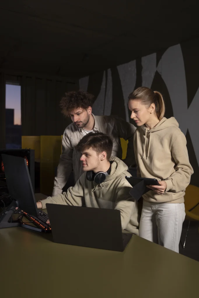 A team of three young web designers, two men and one woman, collaborating on projects in their modern headquarters office.
