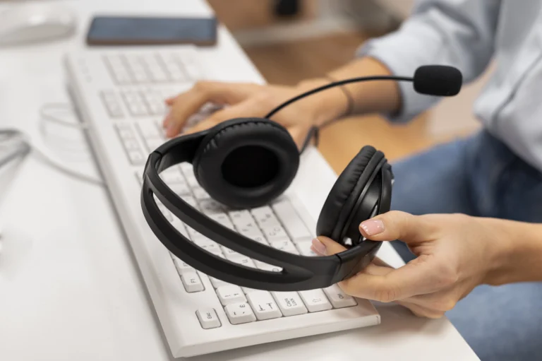 Woman holding her black headset while typing with her other hand on the keyboard